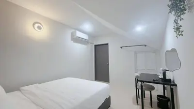 a white bedroom with a bed and a desk at Gather inn in George Town