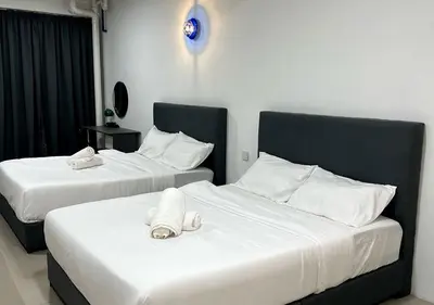 two beds in a hotel room with white sheets at Gather inn in George Town
