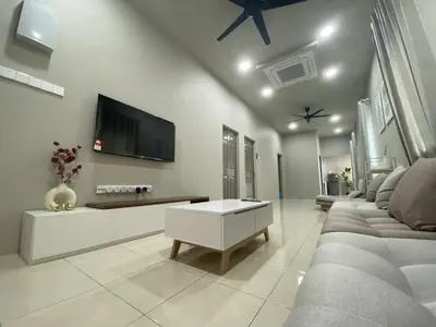 a living room with a couch and a tv on a wall at Cozy Corner House, Bandar Utama in Gua Musang