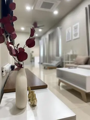 a white vase with red flowers in a living room at Cozy Corner House, Bandar Utama in Gua Musang