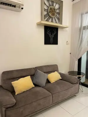 a couch in a living room with a clock on the wall at Oasis Condominium Ipoh in Ipoh