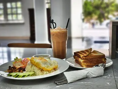 a table with two plates of food and a drink at Pahang Rest House Raub in Raub