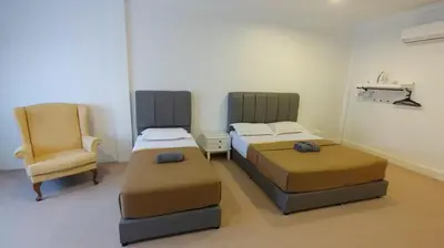 two beds and a chair in a room at Pahang Rest House Raub in Raub