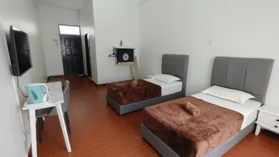 a bedroom with two beds and a table and a chair at Pahang Rest House Raub in Raub