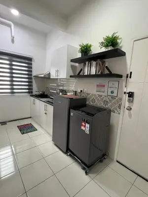 a kitchen with white cabinets and a black refrigerator at Ipoh Modern Skyline & Mountain View Suite in Ipoh