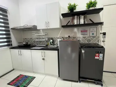 a kitchen with white cabinets and a black refrigerator at Ipoh Modern Skyline & Mountain View Suite in Ipoh