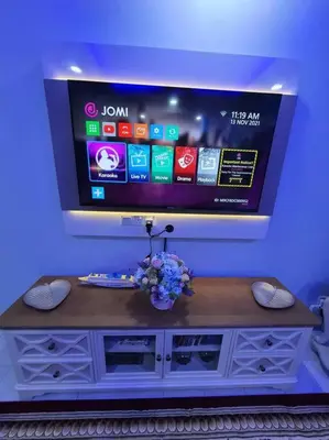a tv on a blue wall with a table with flowers at Lumut Homestay for Muslims in Lumut