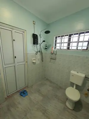a bathroom with a white toilet and a window at Lumut Homestay for Muslims in Lumut
