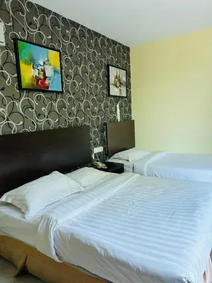 a bedroom with two beds and a tv on the wall at Liner hotel in Simpang