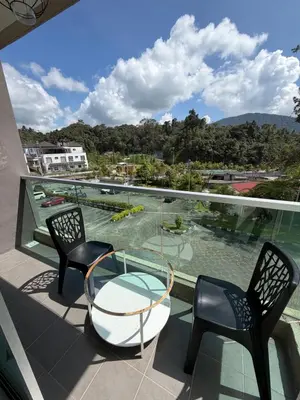 a balcony with a glass table and two chairs at AYAAN ELITE HOME at Quintet Apartment with free parking & Ps4 Gaming and Netflix in Tanah Rata