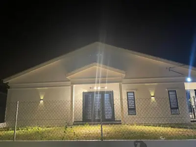 a white house with a fence in front of it at night at Nadine Homestay in Sungai Petani