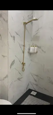 a bathroom with a shower with white marble walls at Nadine Homestay in Sungai Petani