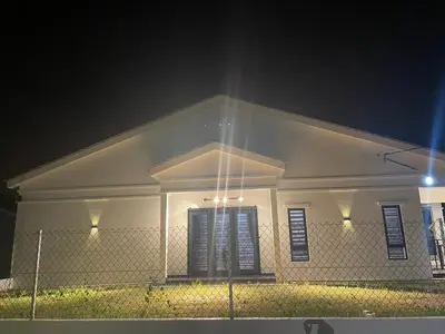 a white house with a fence in front of it at night at Nadine Homestay in Sungai Petani