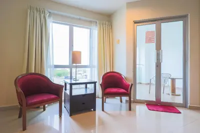 a living room with two chairs and a table and windows at Marina Island Lumut 3 Bedroom Holiday Apartment in Lumut