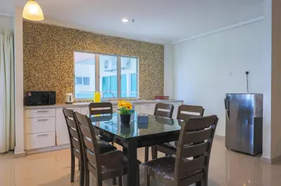a kitchen with a dining room table with chairs at Marina Island Lumut 3 Bedroom Holiday Apartment in Lumut