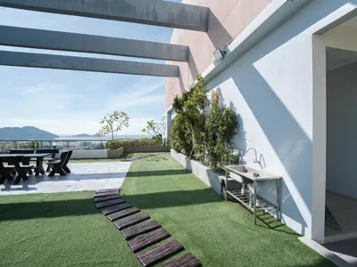 an outdoor patio with grass and a table and chairs at 22 Penthouse by BRB, Airport View & 18 Pax in Bayan Lepas
