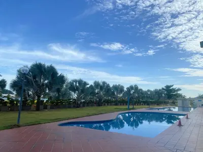 a swimming pool in a park with palm trees at IRONMAN HomeStay in Lumut