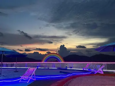 a group of chairs on a beach with a rainbow at IRONMAN HomeStay in Lumut