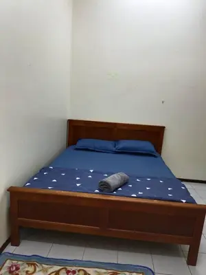 a bed with a wooden frame with a blue comforter and a wooden at Homestay Bajet EM3 Pantai Damai 2 in Pantai Remis