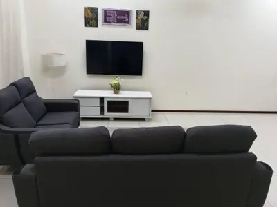 a living room with a couch and a tv at Homestay Bajet EM3 Pantai Damai 2 in Pantai Remis