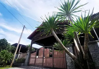 a house with palm trees in front of a fence at Adam Qaisara Homestay in Kulim