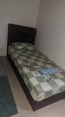 a bed with a checkered comforter on top of it at Sakeena Homestay in Padang Serai