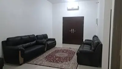 a living room with a black leather couch and a door at Sakeena Homestay in Padang Serai