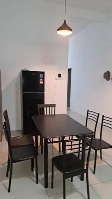 a dining room with a black table and chairs at Sakeena Homestay in Padang Serai