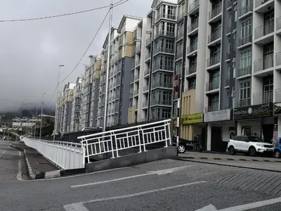 a city street with tall buildings and a white fence at Barrington Square Apartment Pasar Malam in Brinchang