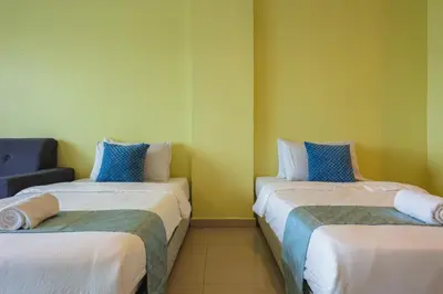 two beds in a room with yellow walls at Marina Island Lumut Homestay in Lumut