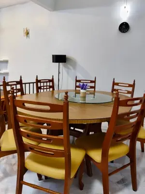 a dining room table and chairs with yellow seats at Grace Homestay Taiping in Taiping