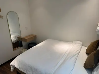 a bedroom with a white bed and a mirror at Domuss Guesthouse- 4B3B Tunas in Bayan Lepas