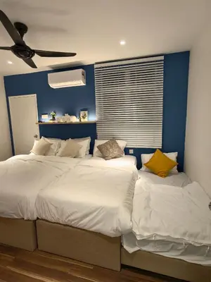 two beds in a bedroom with a blue wall at Domuss Guesthouse- 4B3B Tunas in Bayan Lepas