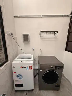 a kitchen with a stove and a washer and dryer at Capy House Taiping in Taiping