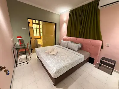 a bedroom with a large bed with a pink headboard at Capy House Taiping in Taiping