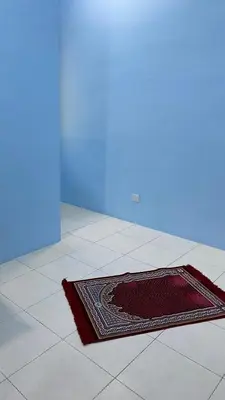 a rug on the floor of a room with a blue wall at UHhomestay in Kampong Tok Bedu