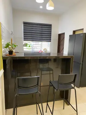 a kitchen with a large counter with four chairs at UHhomestay in Kampong Tok Bedu