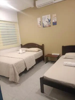 a bedroom with two beds and a window and a table at Ipoh budget house in Ipoh