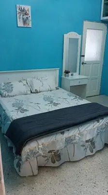 a bedroom with a large bed with a blue wall at Sutera Homestay in Sungai Petani