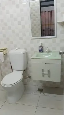 a white bathroom with a toilet and a sink at Sutera Homestay in Sungai Petani