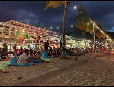a group of people sitting on the beach at night at By the sea Beach Front, Seaview And Pool side in Batu Ferringhi