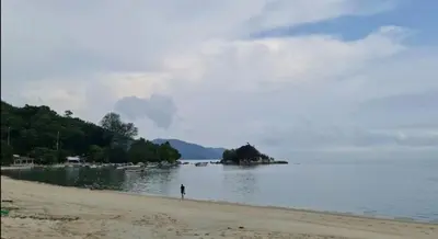 a person standing on a beach near the water at By the sea Beach Front, Seaview And Pool side in Batu Ferringhi