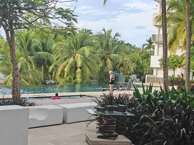 a woman standing by the pool at a resort at By the sea Beach Front, Seaview And Pool side in Batu Ferringhi
