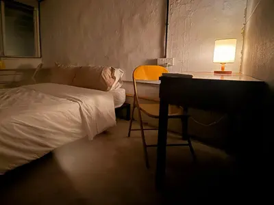 a bedroom with a bed and a desk with a lamp at Just House - Rooms & Curios in George Town