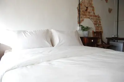 a white bed with white sheets and pillows at Just House - Rooms & Curios in George Town