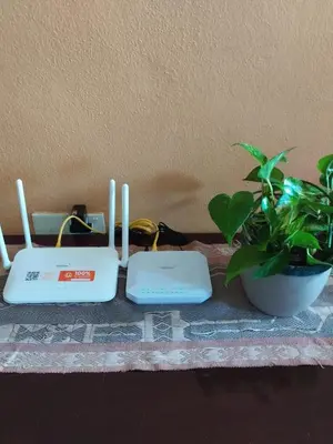 a table with two laptops and a potted plant at Jean CleanComfy Apt Near Beach in Batu Ferringhi