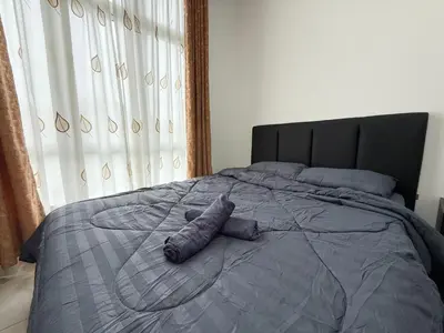 a bed with a gray comforter with a stuffed animal on it at Ipoh Town 3pax Suite The Anderson Residence #516 in Ipoh