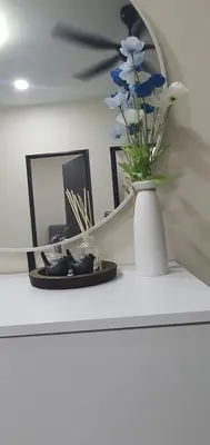 a table with a vase with blue flowers and a mirror at REZEKI MUEZZA 3BR2B Cozy Homestay in Teluk Intan
