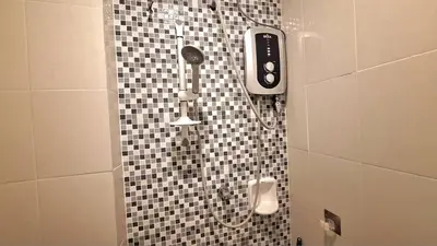 a shower in a bathroom with a black and white tiled wall at A well-kept unit with four bedrooms and ensuite bathrooms in Kampar