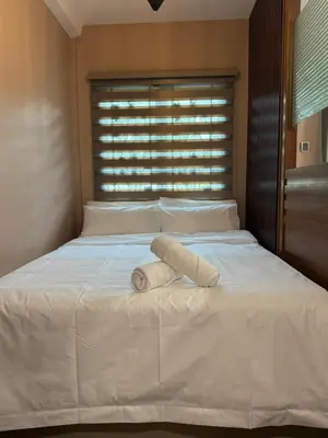 a white bed with a rolled up towel on it at Ichinichi Home in Ipoh